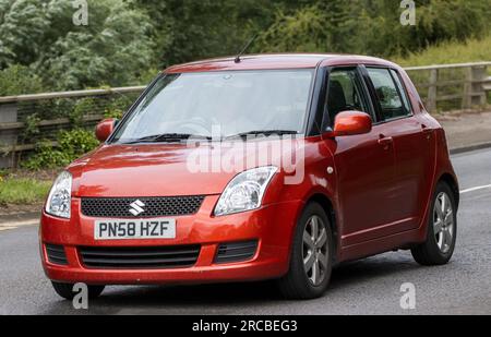 Milton Keynes, UK - Juli 13. 2023: 2008 orangefarbenes SUZUKI SWIFT Auto, das auf einer englischen Straße fährt Stockfoto