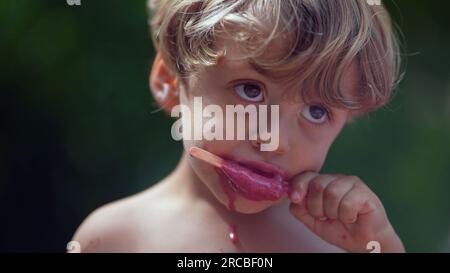 Ein Kind isst Eis draußen während des Sommers, ein kleiner Junge isst süßes Dessert Stockfoto