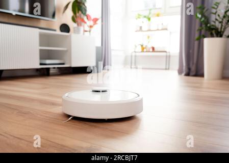 Weißer Roboter-Staubsauger auf dem Boden im Wohnzimmer, Smart-Home-Gerät Stockfoto