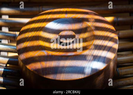 Braune runde Box mit Holzmuster im Licht, das durch die Jalousien gefiltert wird Stockfoto