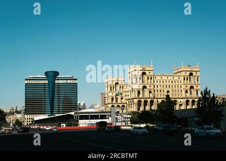 Baku, Aserbaidschan - 26. Juni 2023: Ein eindrucksvolles Bild, das in der Morgendämmerung mit dem historischen Regierungsgebäude neben dem zeitgenössischen Hilton Hotel, Pres Stockfoto