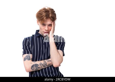 Aufgeregter, pensiver 25-jähriger blonder Mann in gestreiftem Polo auf weißem Hintergrund Stockfoto