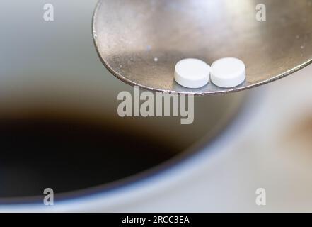 Leipzig, Deutschland. 12. Juli 2023. Ein Löffel mit zwei Süßstofftabletten ist über einer Tasse Kaffee zu sehen. Kredit: Hendrik Schmidt/dpa/Alamy Live News Stockfoto