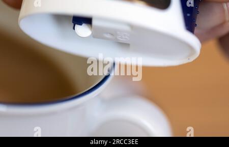 Leipzig, Deutschland. 12. Juli 2023. Eine Süßstofftablette fällt aus einem Spender in eine Tasse Kaffee. Kredit: Hendrik Schmidt/dpa/Alamy Live News Stockfoto