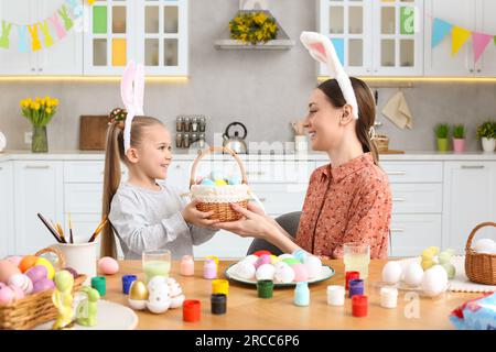 Mutter und ihre süße Tochter mit Korb voller Ostereier in der Küche Stockfoto