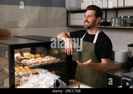 Portrait eines glücklichen Verkäufers an der Kasse in einer Bäckerei Stockfoto