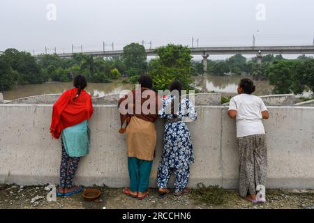 Neu-Delhi, Indien. 12. Juli 2023. Frauen beobachten das Hochwasser, nachdem der Wasserstand des Yamuna-Flusses nach starken Monsunregen in Neu Delhi gestiegen ist. Der Wasserstand von Yamuna in Delhi erreicht eine einmalige Höhe von 207,55 Metern. Die Regierung warnte vor Überschwemmungen und bat die Bewohner des Flussbetts und der tief liegenden Gebiete, ihre Häuser zu evakuieren. Kredit: SOPA Images Limited/Alamy Live News Stockfoto