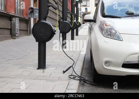 Stockholm, Schweden - 13. Juli 2023: Öffentliche Ladestationen, die von Qwello betrieben werden und zum Parken von Elektrofahrzeugen auf der Straße installiert sind. Stockfoto