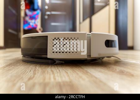 Weißer Roboter-Staubsauger auf Linoleumböden, intelligente Reinigungstechnologie. Selektiver Fokus Stockfoto