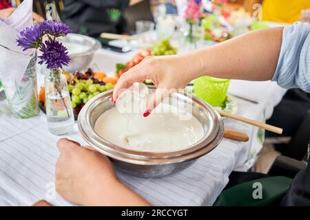 Zu Hause Käse aus Ziegenmilch machen. Weibchen und Käse-Sauerteig mit einem Löffel in einem Kochtopf umrühren. Technologie der Käseherstellung. Käseherstellung Stockfoto