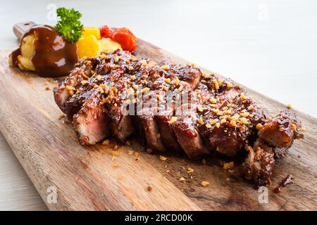 Gegrilltes Schweinesteak mit Tomaten, Ananas und Kartoffelpüree auf Holzplatte aus nächster Nähe. Stockfoto