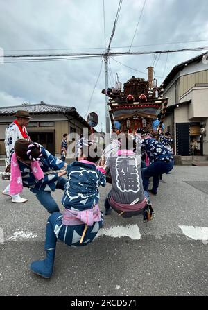 14. Juli 2023, Japan, Sawara: Auf riesigen Holzrädern und begleitet von traditioneller Flöten- und Trommelmusik ziehen Hunderte von Japanern mächtige Wagen durch eine alte Handelsstadt beim Sawara Grand Festival, einem der größten Volksfeste in der Kanto-Region um Tokio. Zu Beginn des dreitägigen Sawara Grand Festivals schubsten und zogen Festivalteilnehmer in traditionellen Kostümen die „Dashi“-Wagen aus dekoriertem Holz, auf denen kostbare Meter hohe Gottheiten, berühmte Samurai oder sogar Tiere verzaubert wurden, und sangen fröhlich durch die Gassen der Altstadt Stockfoto