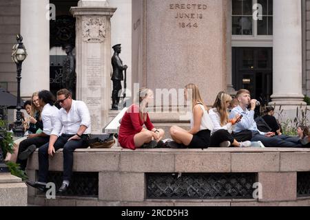 Londoner, die in der City of London, dem Finanzviertel der Hauptstadt, arbeiten, verbringen ihre Mittagspause am 13. Juli 2023 außerhalb von Royal Exchange in London, England. Stockfoto