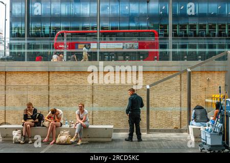 Ein Doppeldeckerbus in der Ferne, in dem Fußgänger vor dem Bahnhof Paddington in London, Großbritannien, Platz nehmen Stockfoto