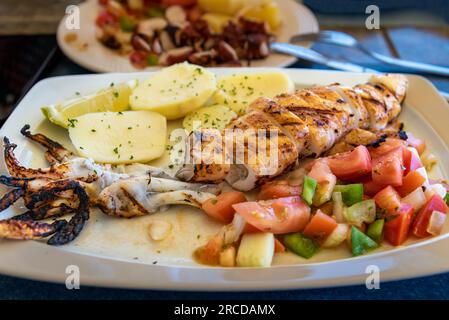 Gegrillter Tintenfisch mit gekochten Kartoffeln und Gemüse, serviert in einem Restaurant an der Algarve. Stockfoto