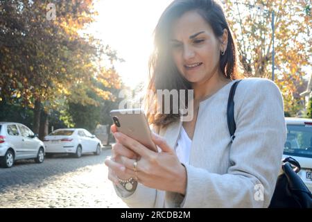 Frau, die ein Smartphone benutzt, während sie auf der Straße steht Stockfoto