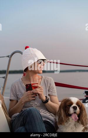 Junge Frau auf einer Jacht mit einem Hund, Cavalier König Charles Spaniel Stockfoto