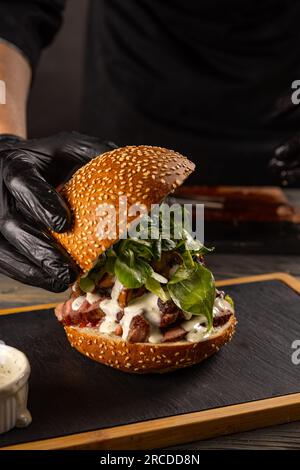 Nahaufnahme der Hand des Küchenchefs bei der Zubereitung eines köstlichen Steak-Burgers Stockfoto