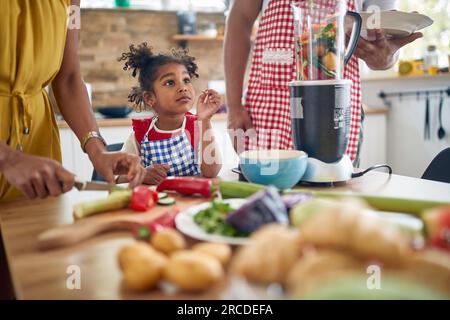 Die afroamerikanische Familie kommt zusammen, um in ihrer Küche eine Mahlzeit zuzubereiten. Das Bild zeigt eine Mutter, einen Vater und eine Tochter, die zusammenarbeiten, Su Stockfoto