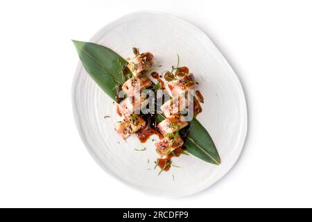 Moderne asiatische Sushi-Rolle mit Aal auf weißem Teller auf weißem Betonhintergrund Stockfoto