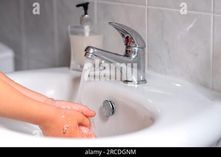 Ein Kind, das sich vor dem Essen im Bad die Hände wäscht. Hygiene, Sauberkeitskonzept. Umweltschutz und die Rettung des Planeten Stockfoto