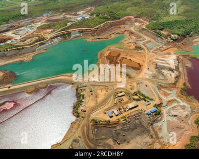 Aus der Vogelperspektive auf einen See mit verschmutztem Wasser in einer Nickelmine. Grüne und burgunderrote Wasserfarbe. Mindanao, Philippinen. Stockfoto