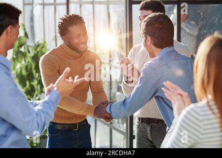 Aufnahme eines glücklichen Geschäftsmannes, der seinen neuen Kollegen während einer Besprechung im Sitzungssaal im Team begrüßt. Stockfoto