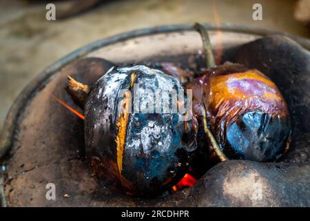 Ganze geröstete Aubergine oder Brinjal in einem traditionellen Tonofen, Angeethi in Nordindien. Zubereitung einer nordindischen Küche, Baigan ka Bharta. In Stockfoto