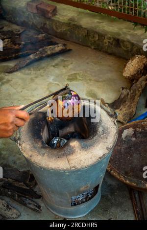 Ganze geröstete Aubergine oder Brinjal in einem traditionellen Tonofen, Angeethi in Nordindien. Zubereitung einer nordindischen Küche, Baigan ka Bharta. In Stockfoto