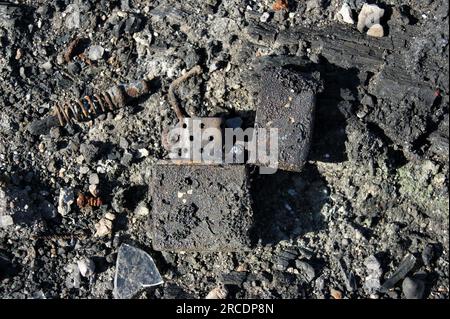 Feuerzeug aus gebranntem Metall in Asche. Die Folgen des Feuers. Nahaufnahme. Stockfoto