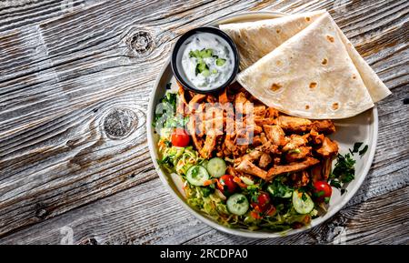 Kebab serviert mit Pita-Brot, Gemüsesalat und Tzatziki. Stockfoto