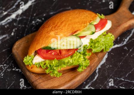 Sandwich mit Käse, Tomaten, Gurke und Salat. Köstliches Sandwich auf dem Servierbrett aus Holz. Schließen Stockfoto