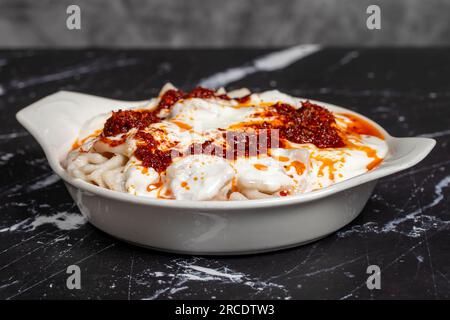 Ravioli mit Sauce und Joghurt. Ravioli auf dunklem Hintergrund. Türkische Köstlichkeiten. Schließen Stockfoto