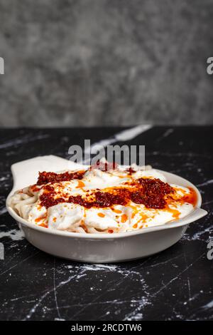Ravioli mit Sauce und Joghurt. Ravioli auf dunklem Hintergrund. Türkische Köstlichkeiten Stockfoto
