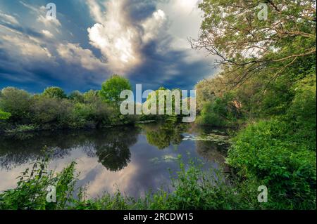 Dramatische Wolkenbildung spiegelt sich auf der Wasseroberfläche des Sees wider Stockfoto