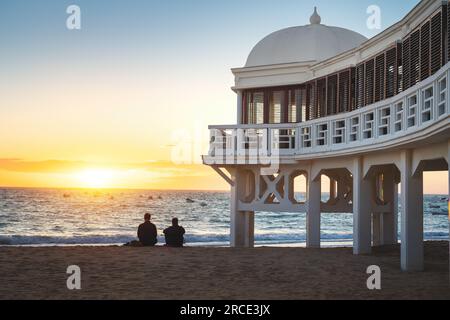 Balneario de la Palma Gebäude am Strand La Caleta bei Sonnenuntergang - Cadiz, Andalusien, Spanien Stockfoto