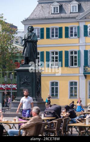 Bonn, Deutschland - 22. Mai 2023 : Blick auf die Statue von Ludwig van Beethoven, ein Bistro-Restaurant und das Deutsche Postgebäude im Hintergrund in Bonn Stockfoto