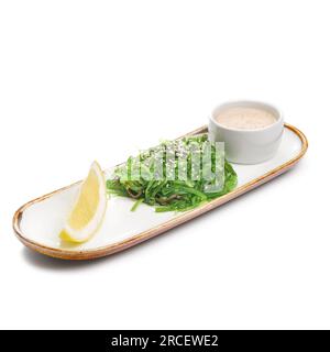 Chuka-Salat auf einem Teller. Zutaten: Mariniertes Seetang, Erdnusssoße, Zitrone, Sesammischung. Speisekarte im Restaurant. Stockfoto