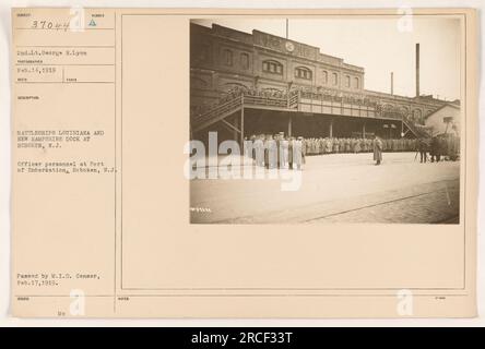 Offizierspersonal versammelt sich am 14. Februar 1919 im Hafen der Einschiffung in Hoboken, New Jersey. Das Foto zeigt die im Hintergrund angedockten Schlachtschiffe Louisiana und New Hampshire. Dieses Bild wurde während des Ersten Weltkriegs aufgenommen und erhielt die offizielle Genehmigung vom M.I.D. Zensor am 17. Februar 1919. Stockfoto