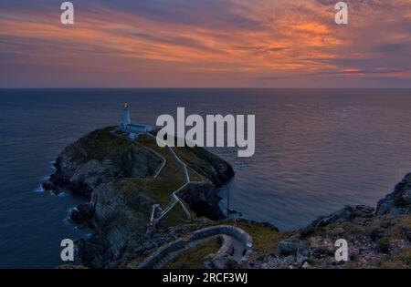 Der South Stack Lighthouse an der Nordwestküste von Anglesey ist berühmt für seine spektakulären Sonnenuntergänge. Stockfoto