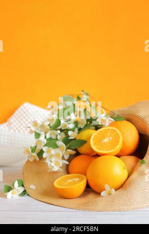 Reife Orangen in einem Sommerhut. Sommerkomposition mit selektivem Fokus. Lebensmittel mit vielen Vitaminen. Vitamin-C-reiche Lebensmittel. Kopierraum Stockfoto