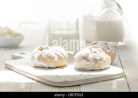 Brötchen, Milch und Hüttenkäse auf einem weißen Holzfrühstückstisch. High Key-Foto Stockfoto