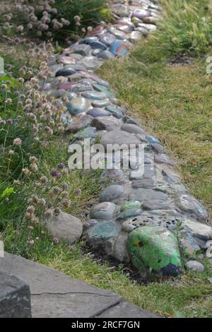 Clevedon, Großbritannien. 14. Juli 2023. An einem feuchten Nachmittag wurde ein Schild mit der Überschrift, dem Clevedon Cobra, entdeckt. Die Schlangenart wurde aus bunten Kieseln und Steinen mit Botschaften wie sicher bleiben, gesund werden, glücklich sein alles in Erinnerung an den Lockdown während der Covid -19 Pandemie. Bildnachweis: Robert Timoney/Alamy Live News Stockfoto