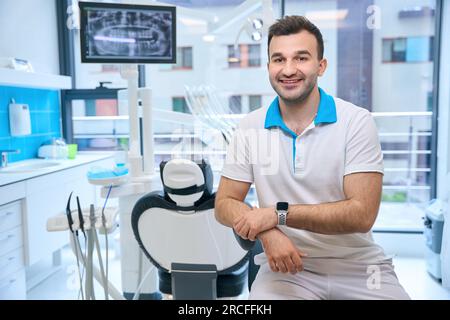 Lächelnder Mann am Arbeitsplatz in der Zahnarztpraxis Stockfoto