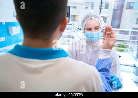 Die Assistentin in der Operationsuniform bereitet einen Chirurgen auf die Operation vor Stockfoto