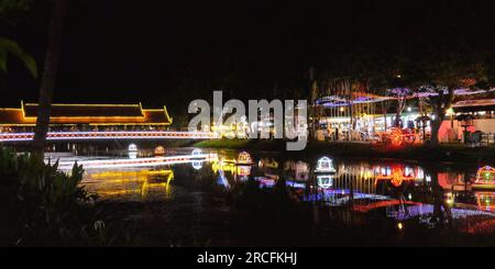 Eine farbenfrohe beleuchtete Brücke über einen kleinen Fluss in der kambodschanischen Stadt Siem Reap, farbenfrohe Reflexionen der Nachtlichter auf der Wasseroberfläche. Stockfoto