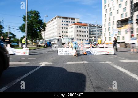 14. Juli 2023, blockierte Aktivist*innen der letzten Generation am Stachus in München, Deutschland. Einige klebten sich fest und einer betonte sich an die Straße fest. Die Letzte Generation fordert ein Tempolimit von 100 km/h auf Autobahnen, die Einführung eines Neun-Euro-Tickets und einen Gesellschaftsrat Klima. -- am 14. Juli 2023 blockierten Aktivisten der letzten Generation die Stachus in München. Einige steckten sich selbst fest und einer betonte sich auf der Straße. Die Last Generation fordert eine Geschwindigkeitsbegrenzung von 100 km/h auf Autobahnen, die Einführung eines 9-Euro-Tickets und eines Soc Stockfoto