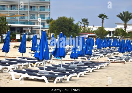 Ayia Napa, Zypern - 4. November. 2018. Leere Sonnenliegen und gefaltete Sonnenschirme im Makronissos Beach Resort. Die Schwimmsaison endet Stockfoto