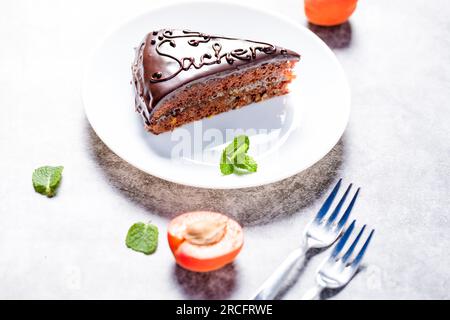 Sachertorte. Traditionelles österreichisches Dessert mit Aprikosenmarmelade und frischen Aprikosen auf hellem Hintergrund Stockfoto