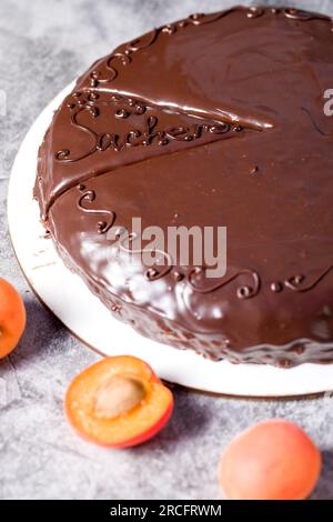 Sachertorte. Traditionelles österreichisches Dessert mit Aprikosenmarmelade und frischen Aprikosen auf hellem Hintergrund Stockfoto